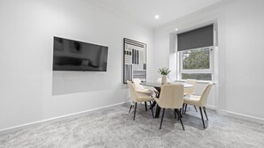 Een moderne vergaderruimte met een ronde tafel, zes stoelen, een flatscreen televisie aan de muur en een raam met uitzicht.