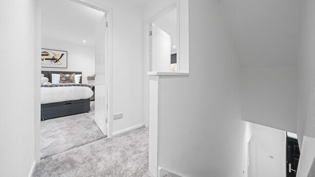 Un dormitorio moderno con cama, mesita de noche y espejo.