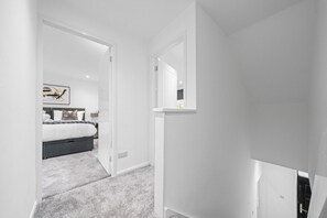 Une chambre à coucher moderne avec un lit, une table de chevet et un miroir.