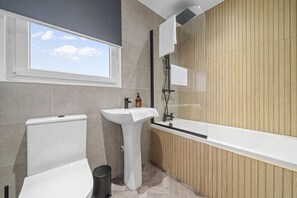 A modern bathroom with a toilet, sink, and bathtub. - Loch Lomond Hillside Retreat (Alexandria)