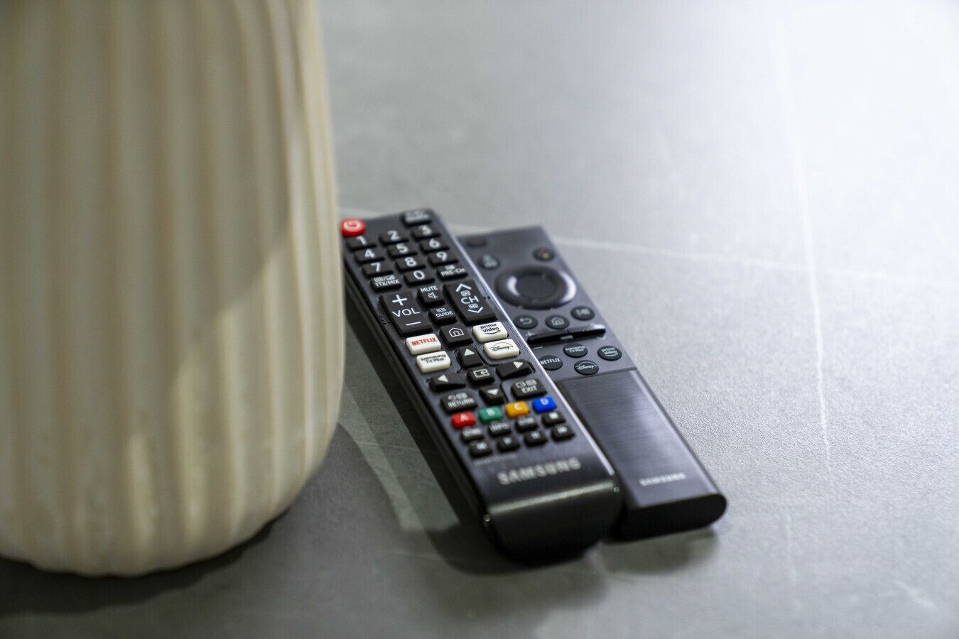 A black remote control with a numeric keypad and directional buttons, placed on a flat surface.