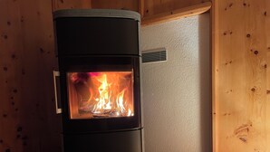 A wood-burning stove in a room with wooden walls and a vent. - Cozy Engadine house with a unique view! (Valchava)