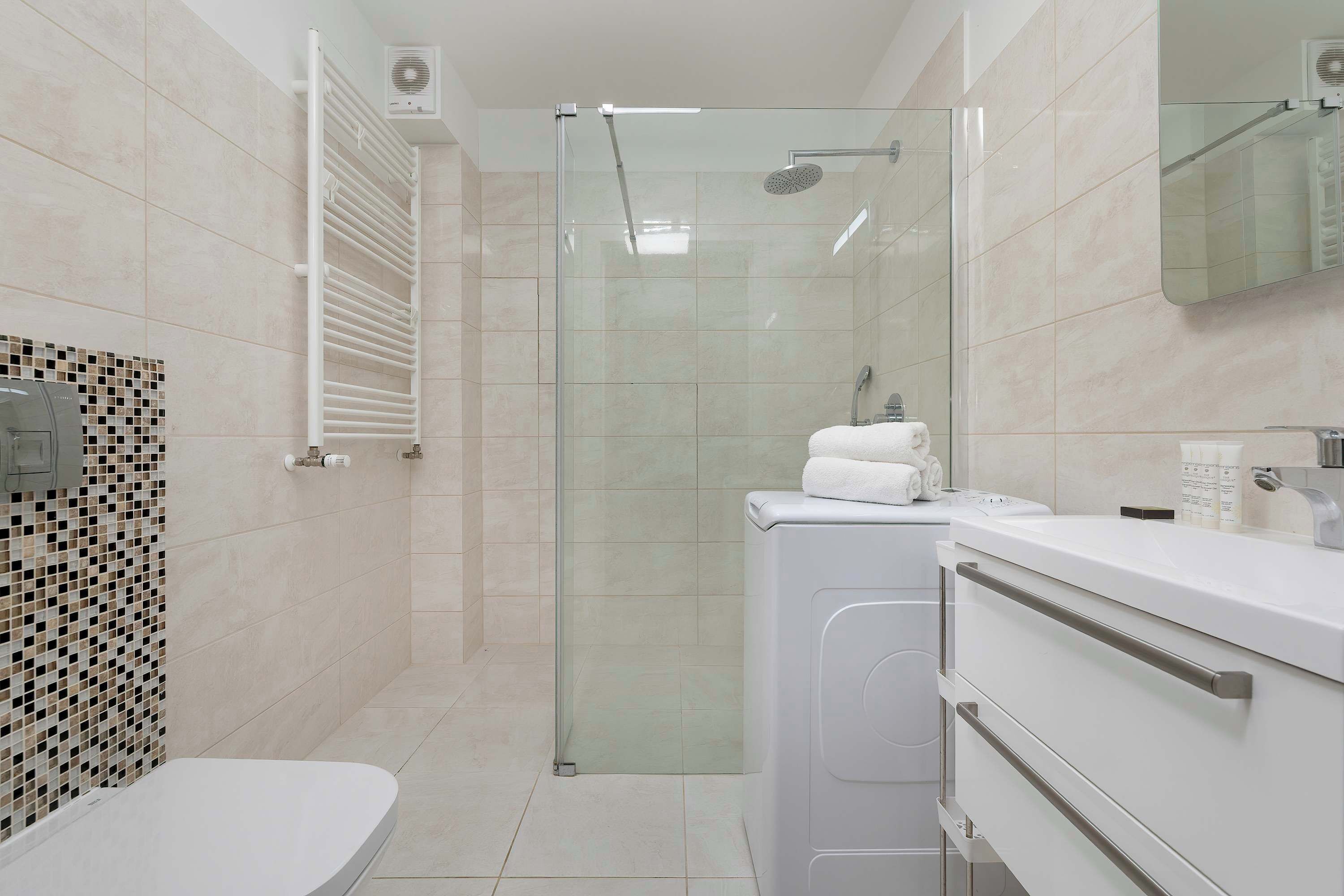 A modern bathroom with a glass-enclosed shower, a toilet, and a sink with a mirror.