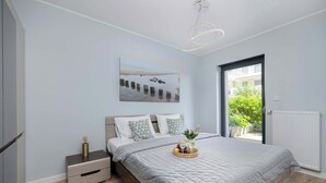 Una camera da letto moderna con un letto grande, un comodino, una lampada da notte e una finestra con vista, illuminata da un lampadario.