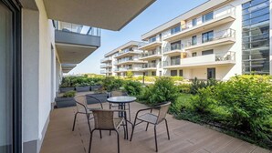 Un moderno edificio residenziale con balconi, arredi esterni e rigogliosa vegetazione.