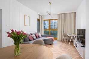 Ein modernes Wohnzimmer mit einer Couch, einem Esstisch und einem Fernseher.