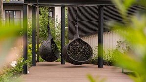 A covered outdoor area with a wooden deck and hanging planters. - Malila Apartments Cracow Rakowicka 254 (Kraków)