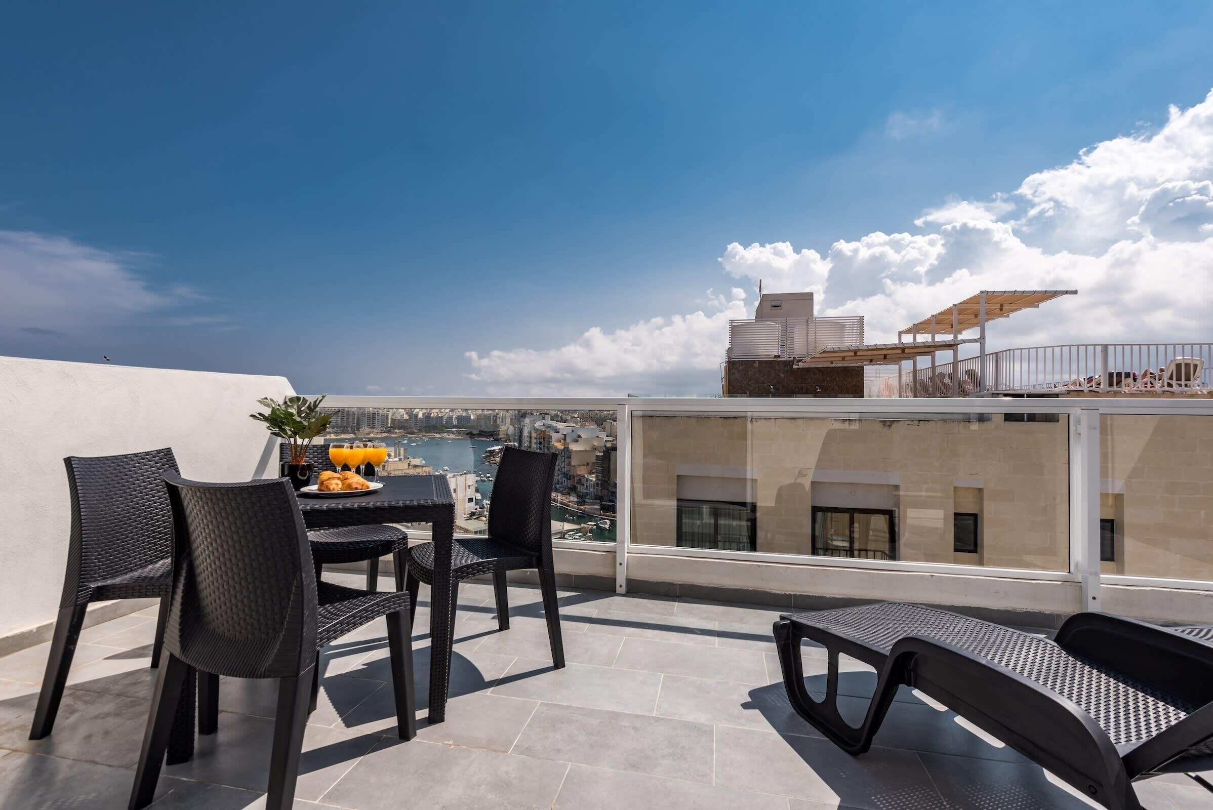 Une terrasse sur le toit avec une table et des chaises, une vue sur la ville et une piscine.