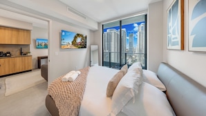 Una habitación de hotel moderna con una cama grande, un escritorio y vistas a edificios altos.