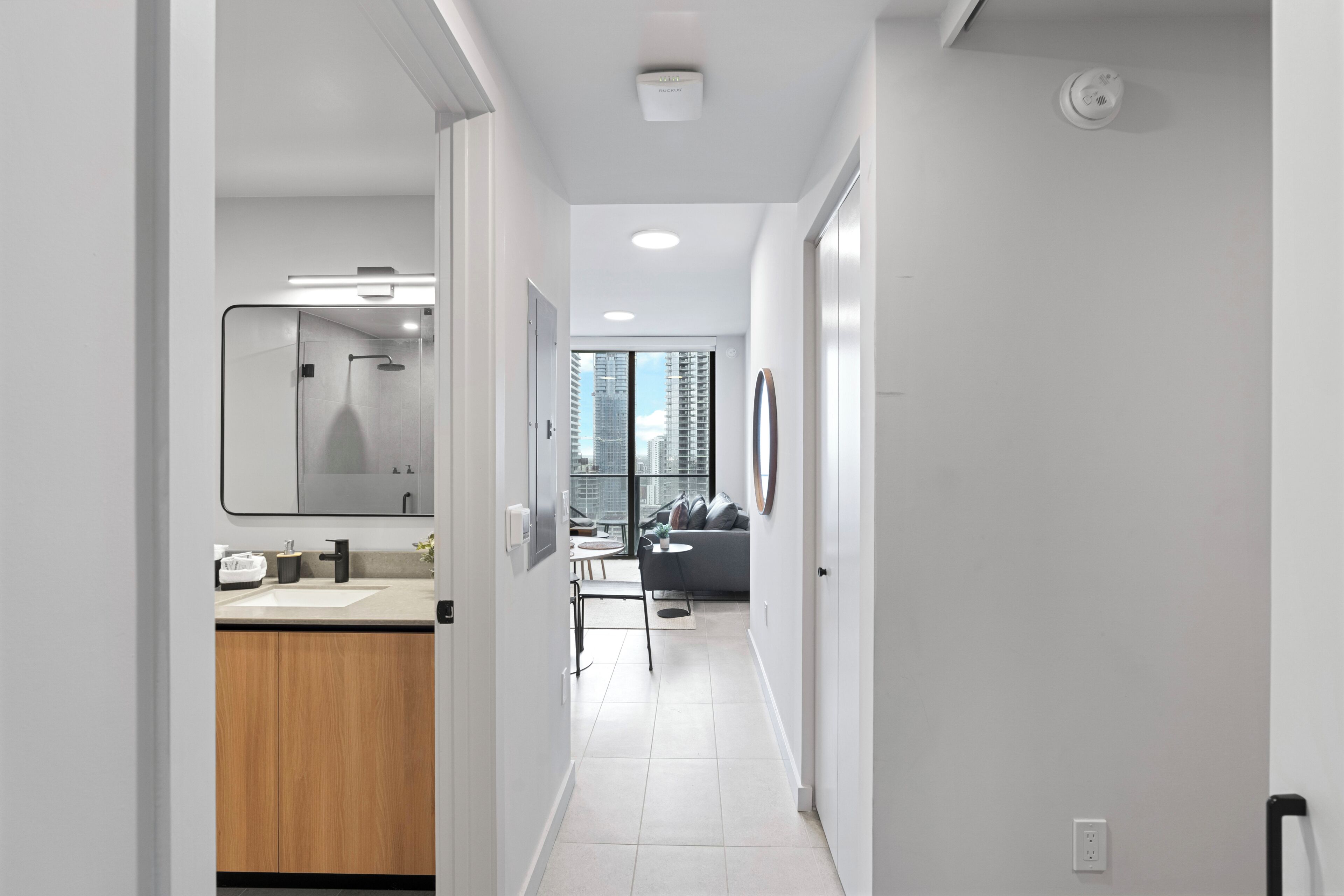 A modern hotel corridor with a bathroom, a dining area, and a view of the city.