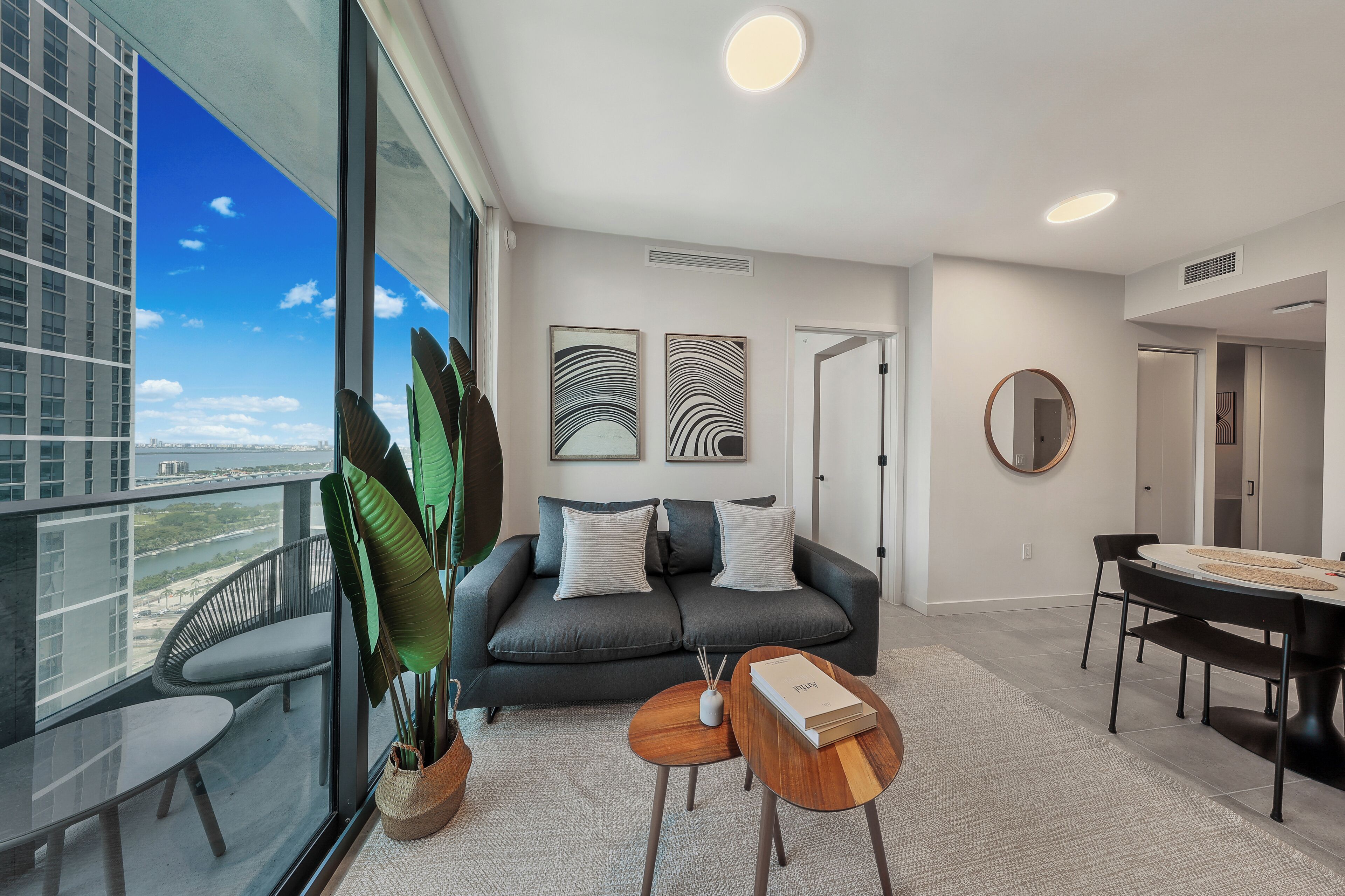 Ein modernes Wohnzimmer mit Balkon, einer Couch, einem Esstisch und Kunstwerken an den Wänden.