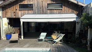 Een houten huis met een overdekt terras en een zwembad.