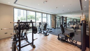 Ett modernt gym med olika typer av träningsutrustning, stora fönster och en vägg med speglar.