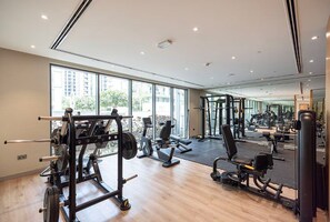Ein modernes Fitnessstudio mit unterschiedlichen Trainingsgeräten, großen Fenstern und einer Spiegelwand.