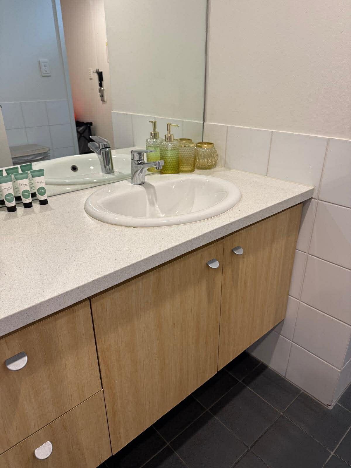 A bathroom with a white sink, wooden cabinets, and a mirror.