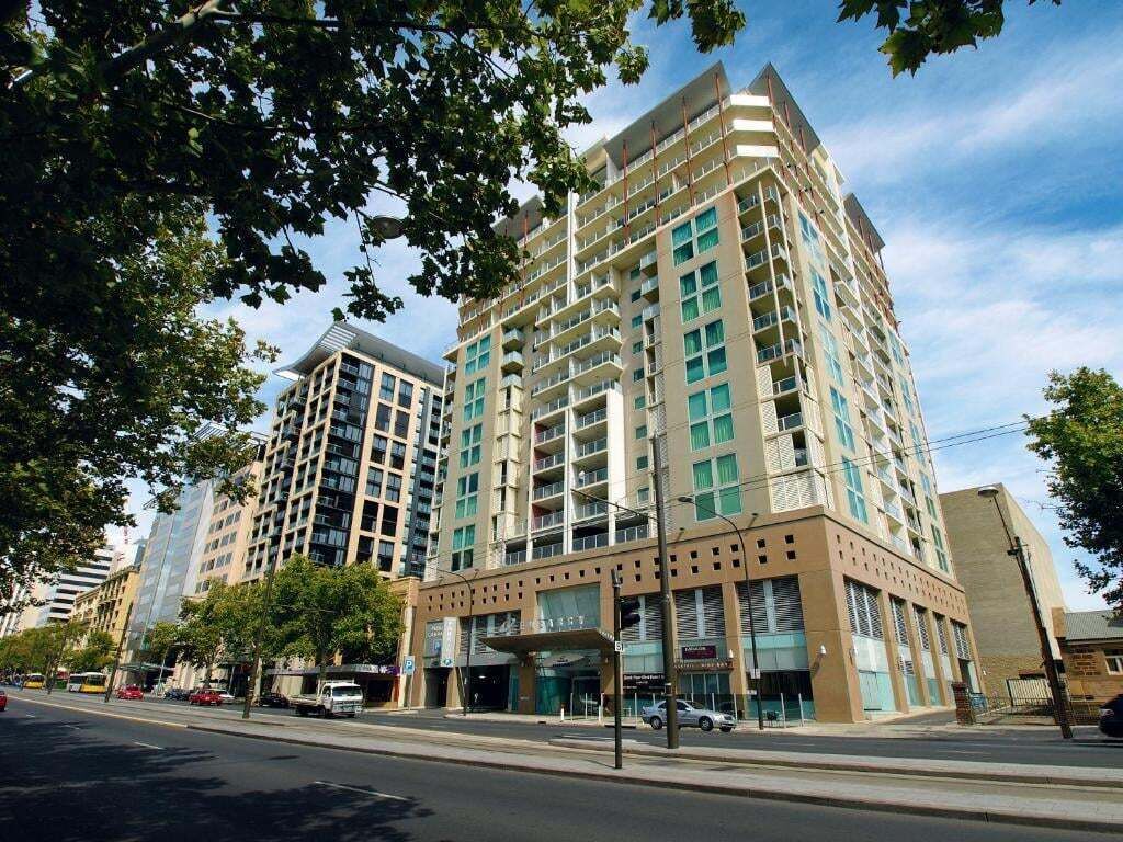 A multi-story hotel with a modern design, featuring a prominent entrance with a covered area and a visible parking lot.