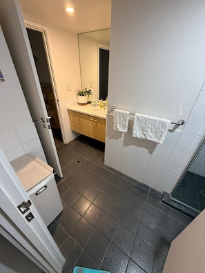 A bathroom with a white sink, a mirror, a towel rack, and a shower area. - Cozy & Affordable in CBD - Free Wine (Adelaide)