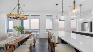 Una cocina moderna con una isla grande, armarios blancos e iluminación colgante.