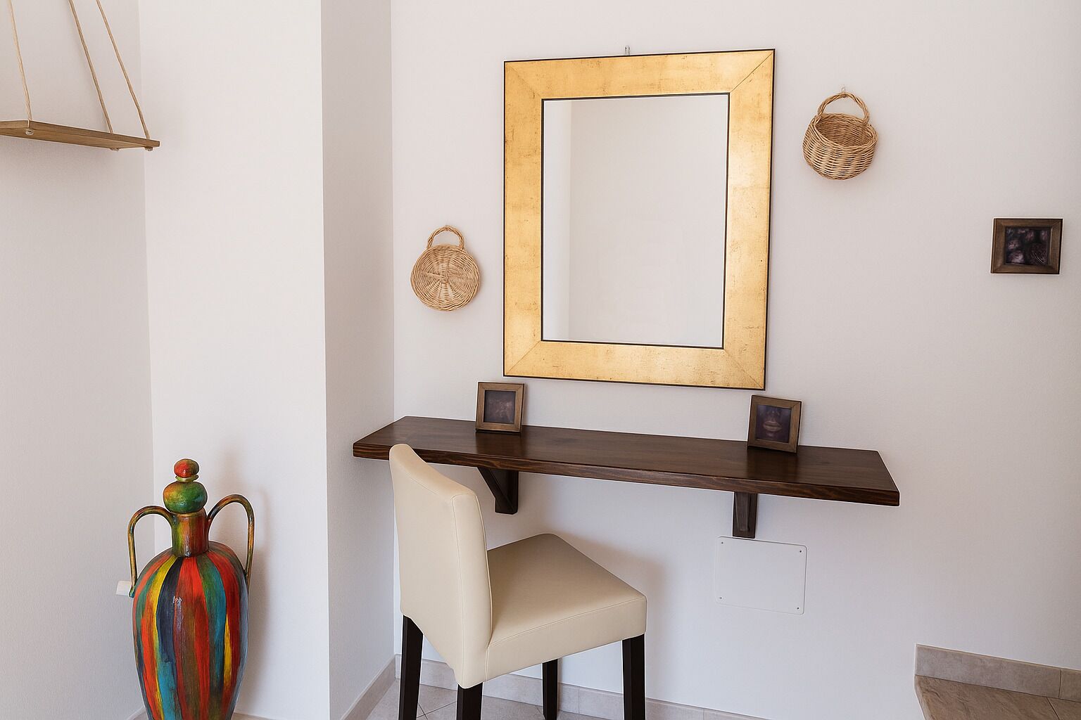 Ein modernes Interieur mit einem dunklen Holzkonsole, einem beigen Sessel, einer farbenfrohen Vase und einem großen Spiegel mit goldener Rahmung.