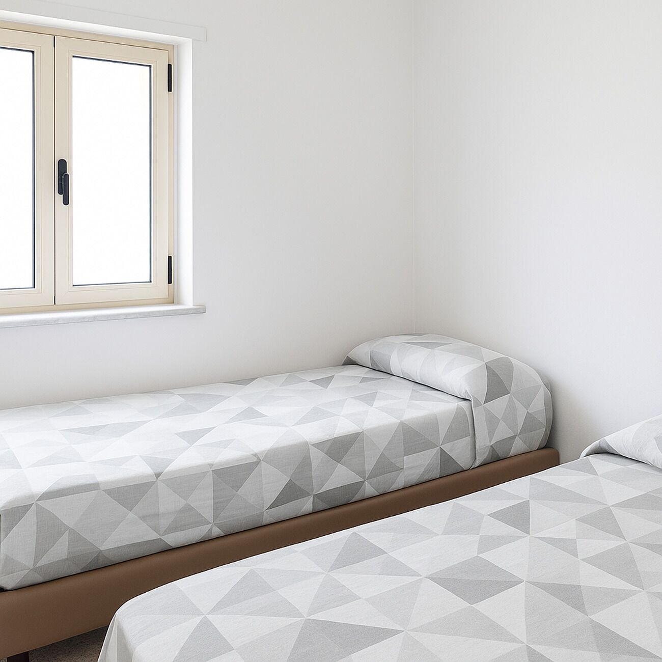 Ein Schlafzimmer mit zwei Einzelbetten, einem Fenster mit Holzrahmen und einer schlichten weißen Wand.