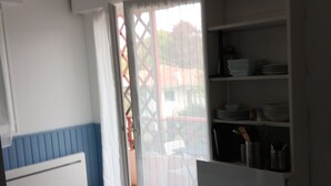 A kitchen with a white cabinet, a blue lower section, and a view through a glass door to an outdoor area.