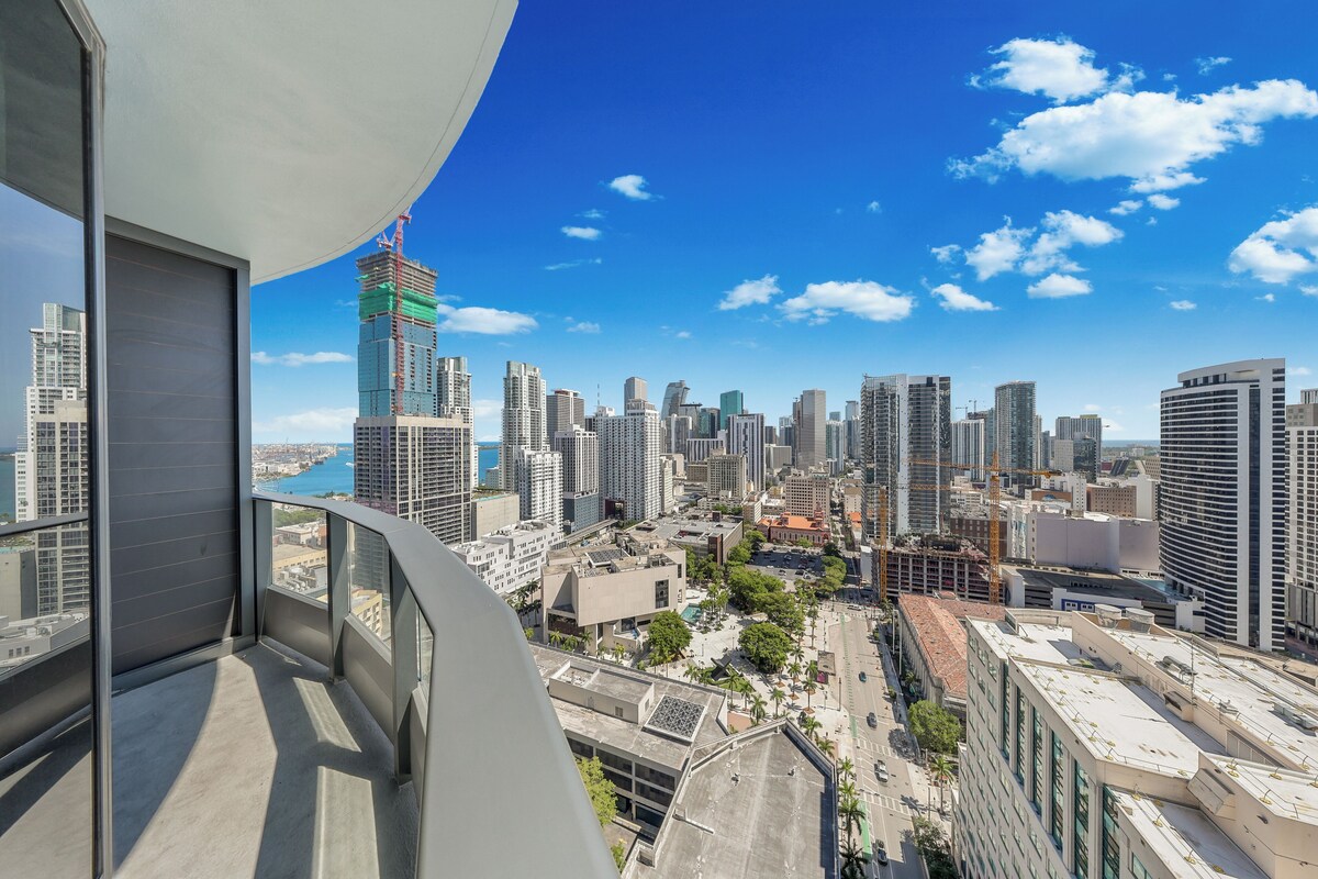 A high-rise building with a view of a cityscape, including a construction site and various buildings.