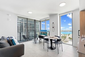 A modern living room with a balcony, a dining area, and a large TV screen. - First Residences - Heart of Miami - We Host (Miami)