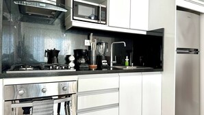 Una cocina moderna con electrodomésticos de acero inoxidable, incluyendo un microondas, horno y cafetera.