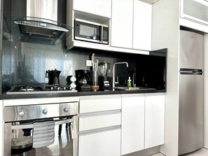 A modern kitchen with stainless steel appliances, including a microwave, oven, and coffee maker. - Soha II Deluxe Suites (Santiago de los Caballeros)