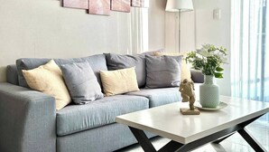 Una sala de estar moderna con un sofá gris, una mesa de centro blanca y una lámpara de pared.