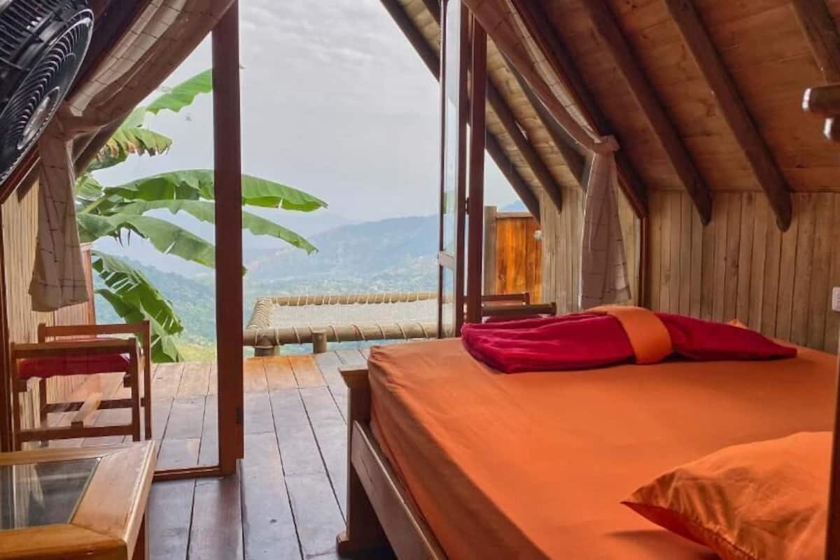 A wooden room with a bed, a table, and a chair.