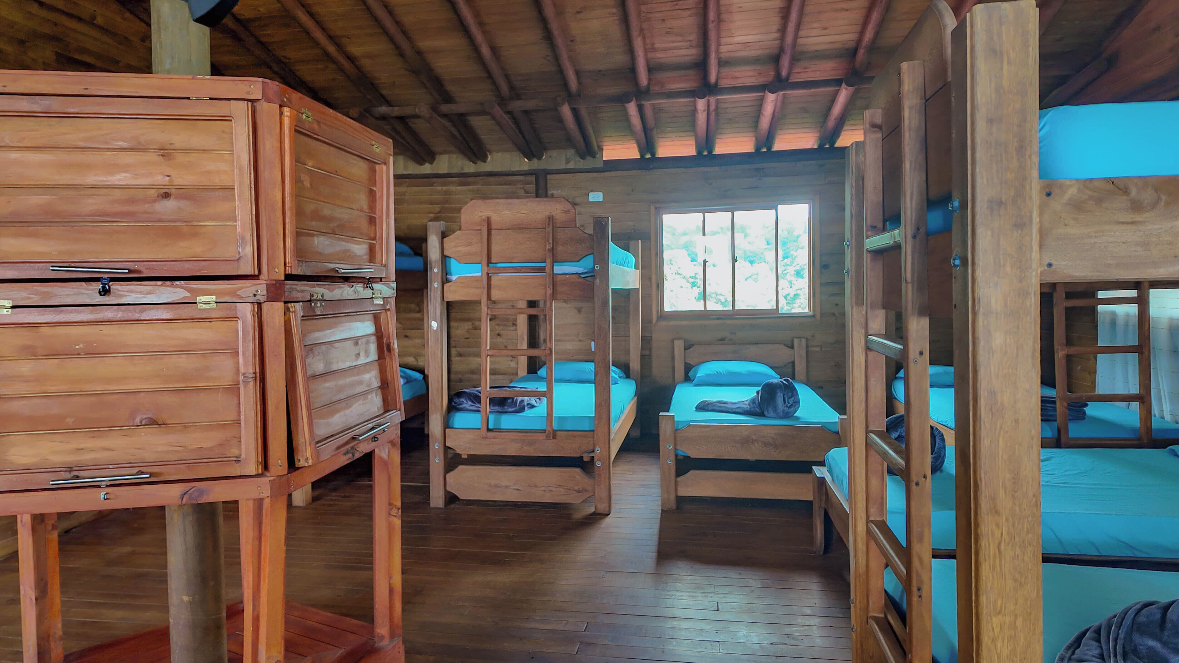 Una cabaña con literas, muebles de madera y una ventana que deja entrar luz natural.