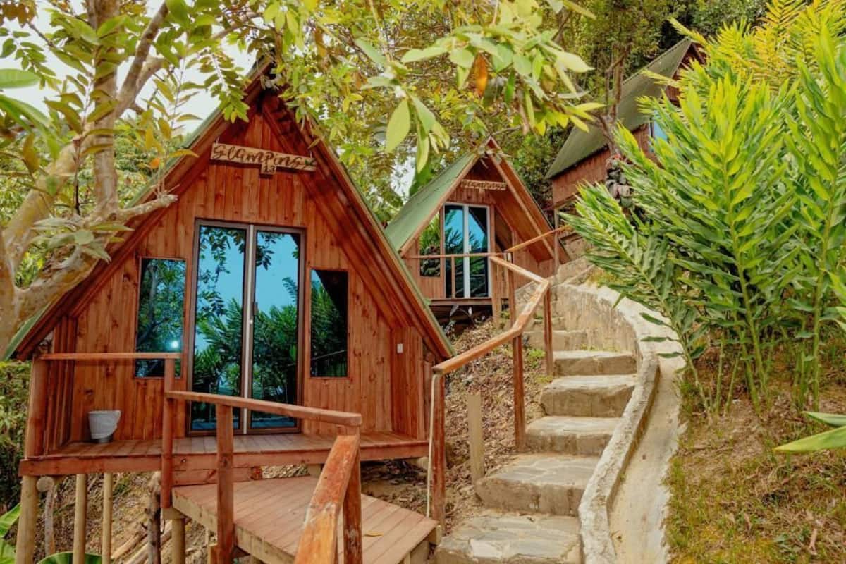 Two wooden cabins with large windows, a wooden deck, and a stone staircase.