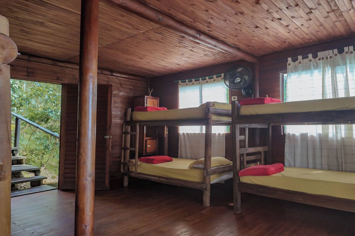 A cabin with bunk beds, wooden floors, and a staircase leading outside.