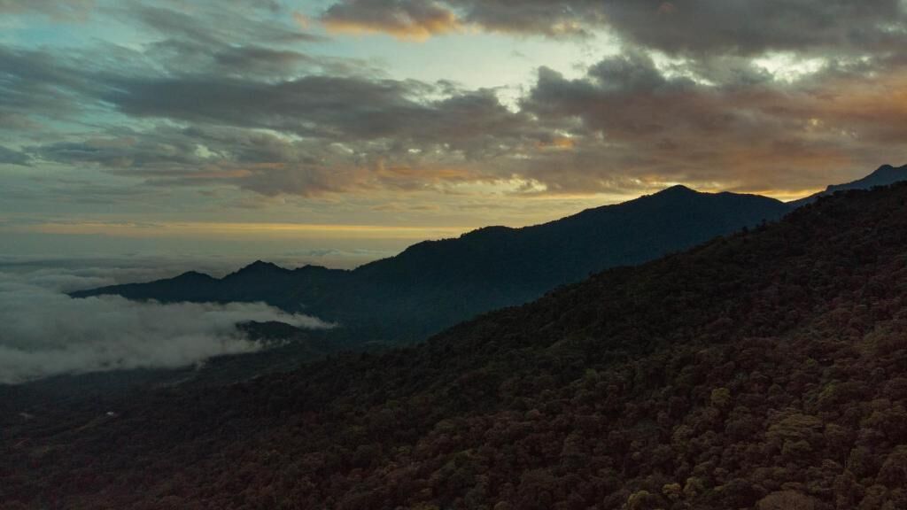A mountainous landscape with a view of distant mountains and a cloudy sky.