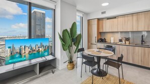 A modern kitchen with a view of a city skyline, a dining area with a round table, and a large window. - 501 Building - Close to Kaseya Center - We Host (Miami)