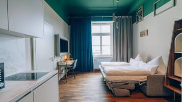 Ein kleiner Raum mit einem Bett, einem Schreibtisch, einem Fernseher und einem fenster mit Vorhängen.