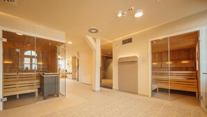 A modern spa with wooden benches and glass partitions, a patterned floor, and recessed lighting. - Hotel Amalia - Boutique Hotel (Landshut)