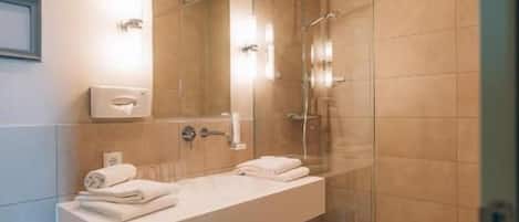 A modern bathroom with a glass-enclosed shower, a white vanity with two sinks, and a large mirror.