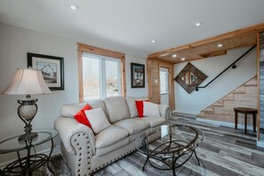 A living room with a sofa, a glass table, a lamp, and a staircase.