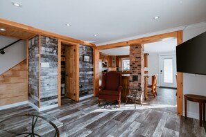 Amplia sala de estar con una escalera de madera, un sillón rojo y un televisor a la derecha.