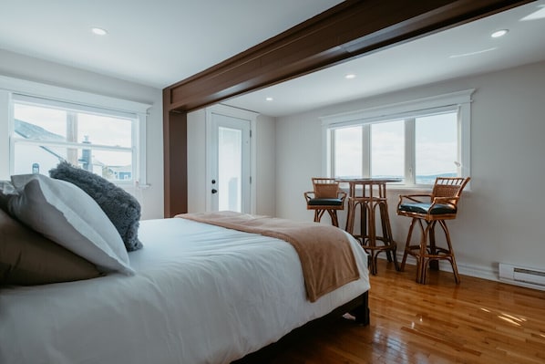 Un dormitorio con una cama grande, una viga de madera en el techo y vistas al exterior a través de una ventana.