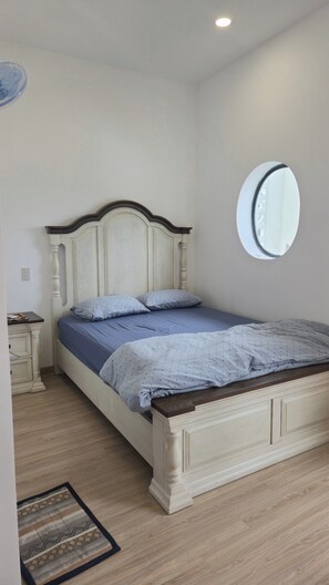 A bedroom with a bed, a bedside table, a mirror, and a small rug. - TP HOMe (Nha Trang)