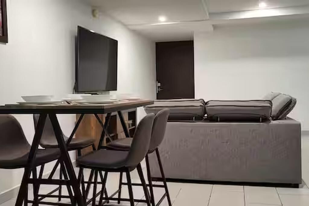 Una sala de estar moderna con un sofá, un televisor y una mesa de comedor con sillas.