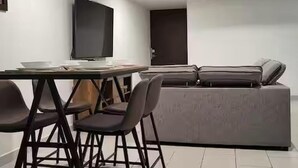 Una sala de estar moderna con un sofá, un televisor y una mesa de comedor con sillas.