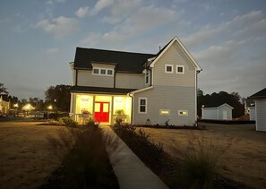 A two-story house with a red door and a covered porch.