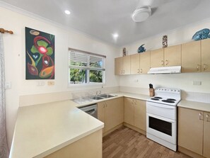 Cocina con lavavajillas, estufa y ventana con persianas.