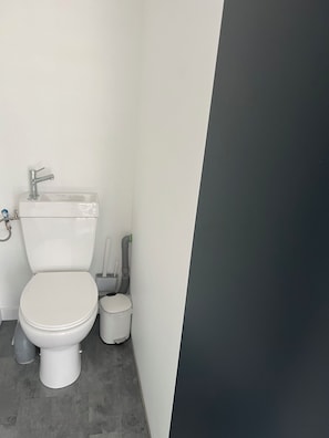 A small, modern bathroom with a toilet, sink, and a toilet brush. - Erdivines – Ma Bro, La Suite, newly renovated studio, sleeps 2–4 – Erdeven (Erdeven)