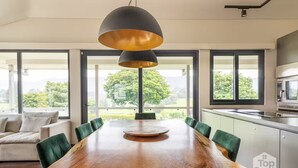 Un espace repas moderne avec une table en bois, des chaises vertes et un luminaire suspendu.