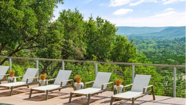 Un espace aménagé au bord de la piscine, avec des chaises longues et une vue sur un paysage montagneux.